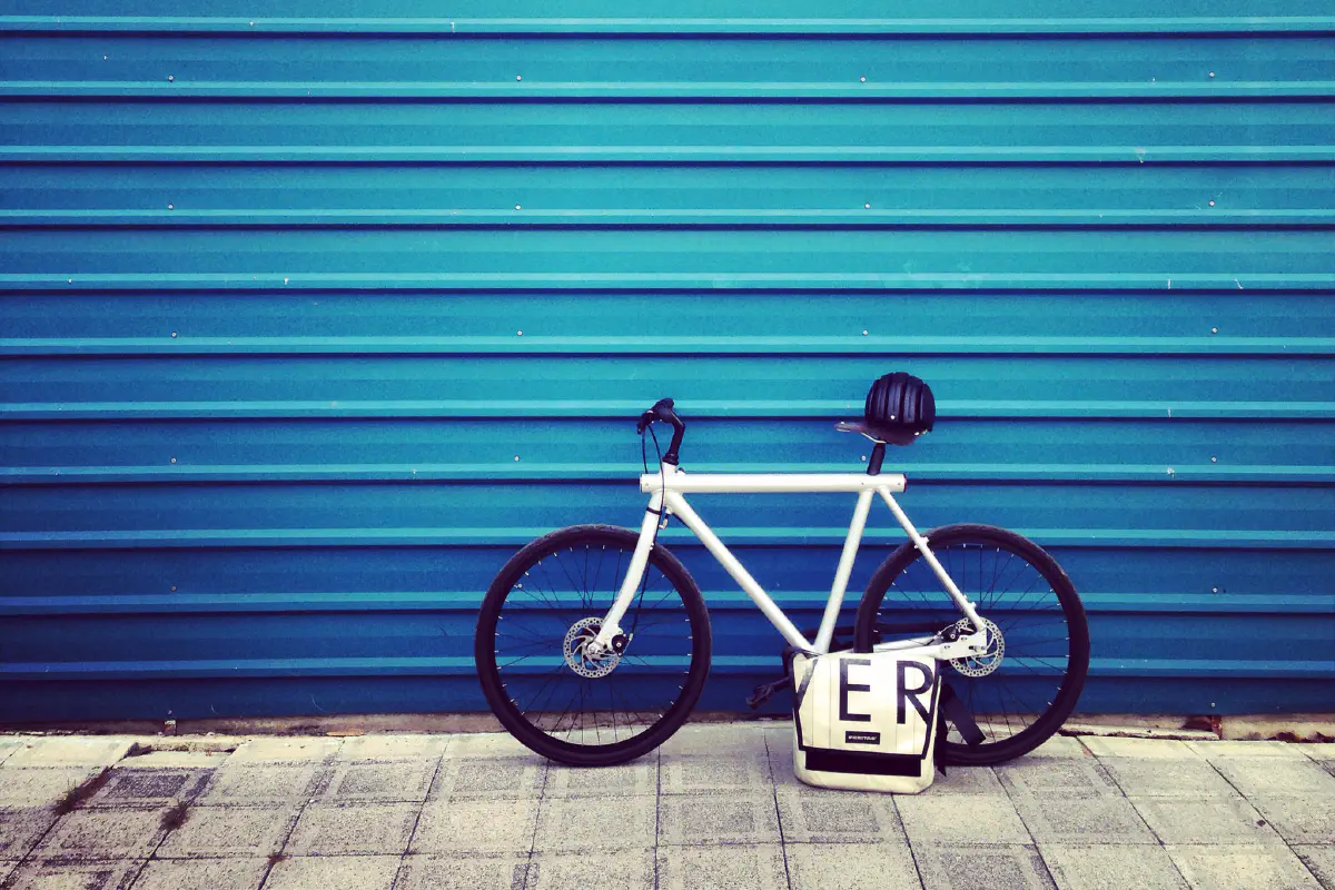 Photo of a white VanMoof bicycle leaning against a blue garage door